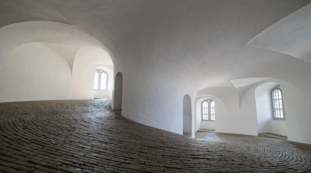 The curved walkway is paved with bricks and topped with white covering