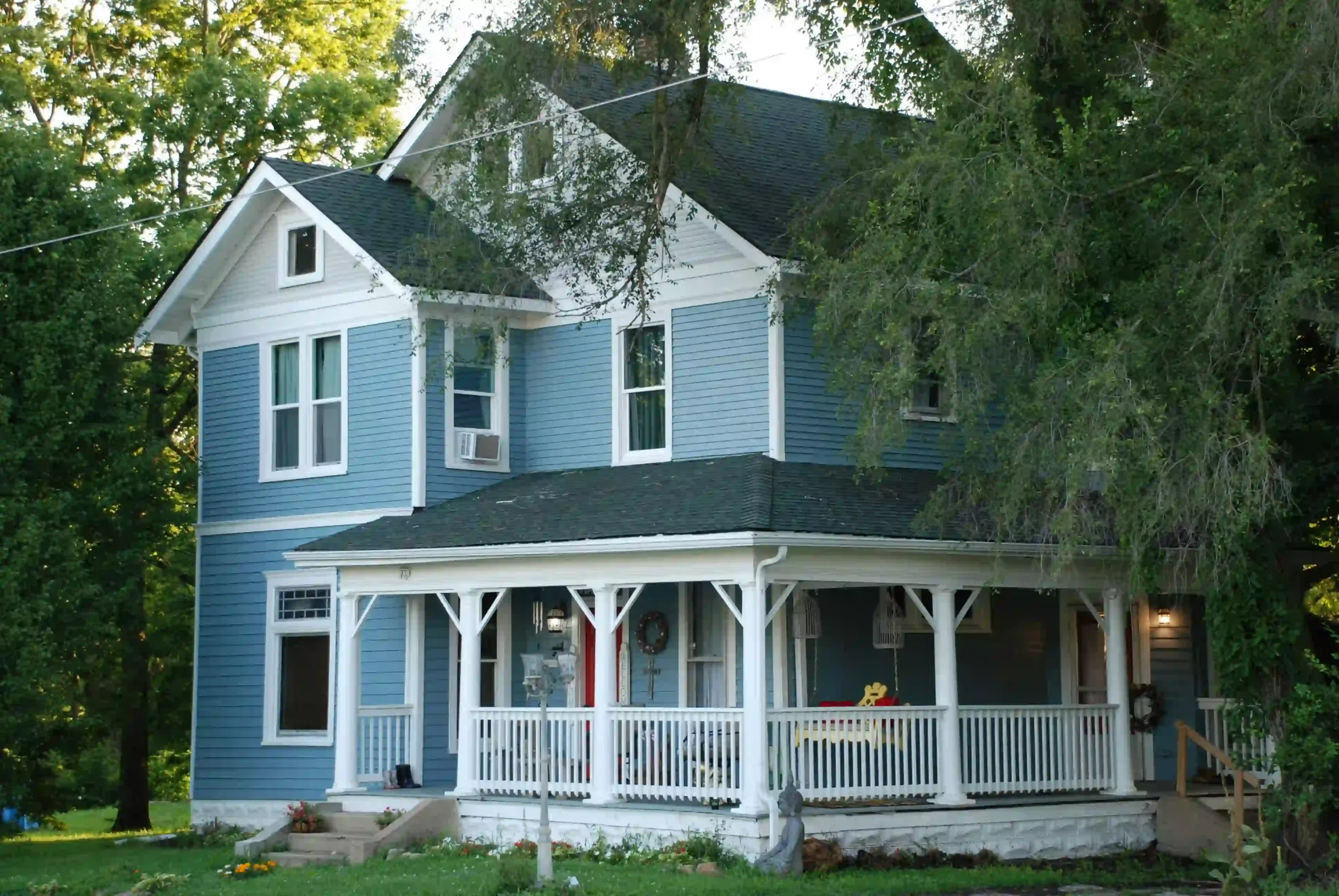 Blue exterior fiber cement board siding on a European-style house surrounded by forest